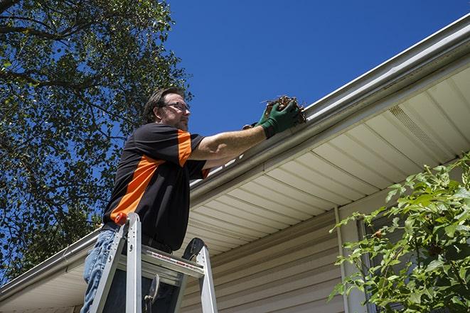 maintenance worker using a ladder to repair a gutter in Dearborn Heights